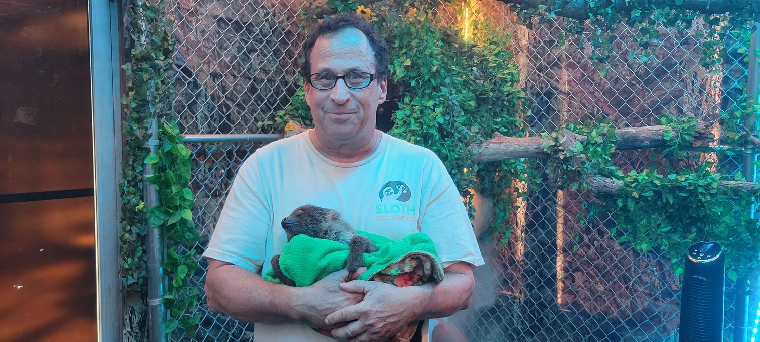 Larry Wallach, owner of Sloth Encounters, holds a sloth in the encounter area.